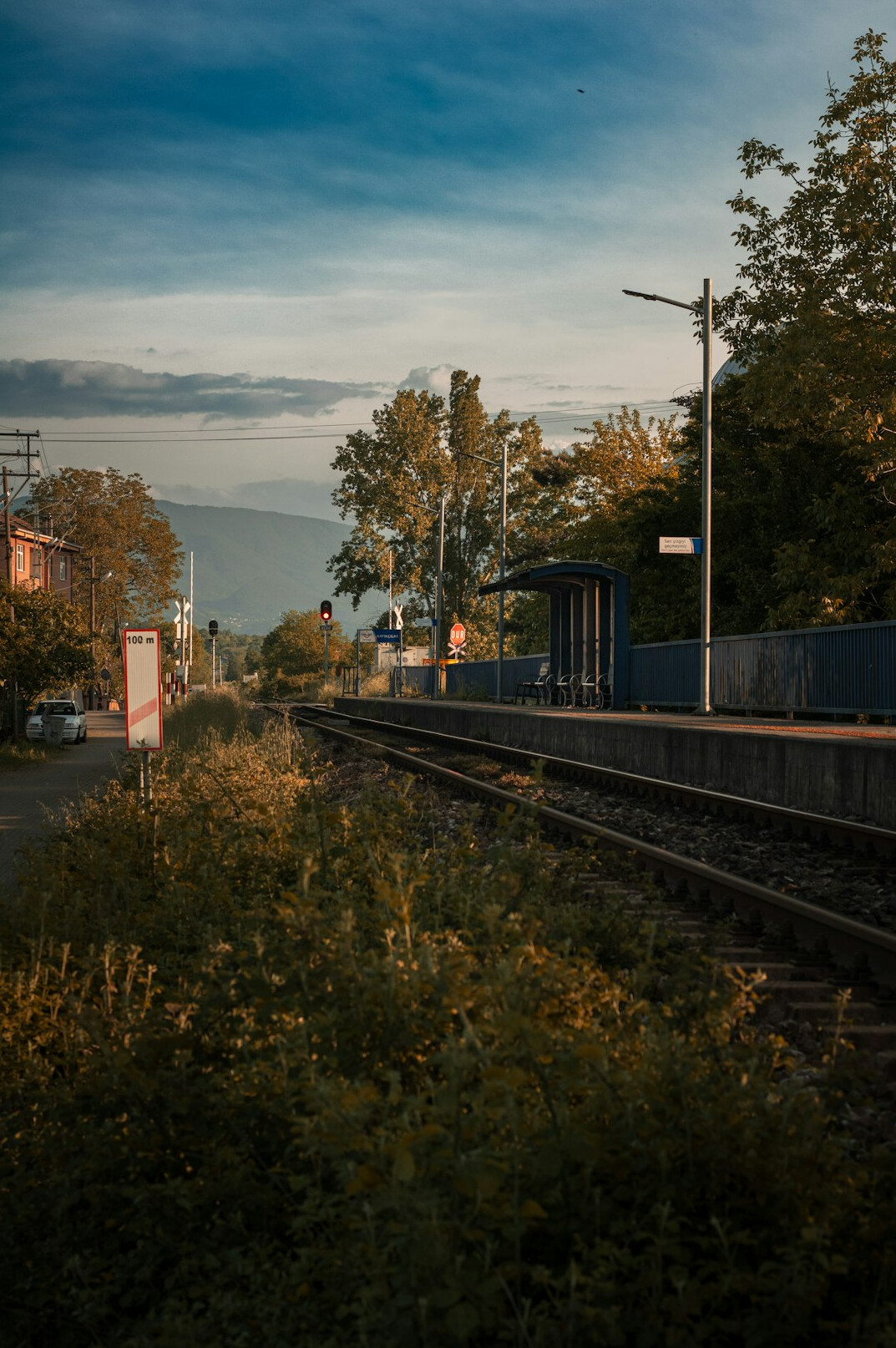 Abandoned old railway station platform with rusty tracks and overgrown grass